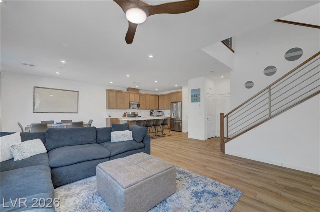 Open-concept living room with custom slatted wood accent wall and ceiling fan