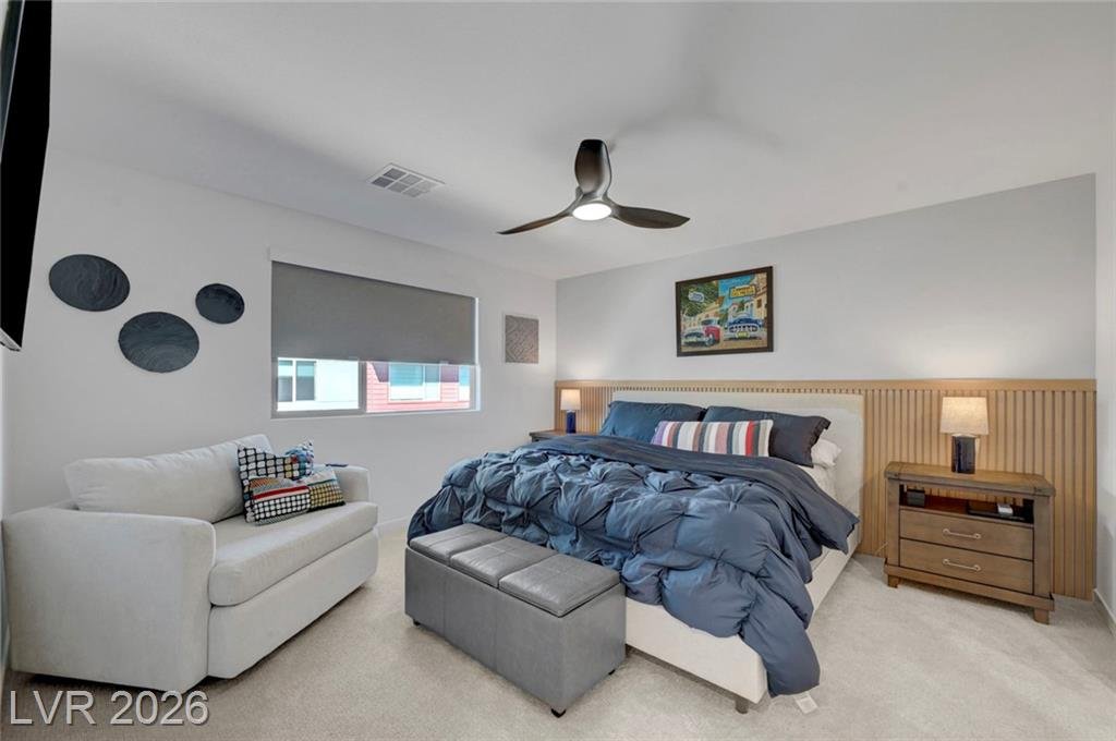 Primary bedroom with ceiling fan and slatted wood headboard wall