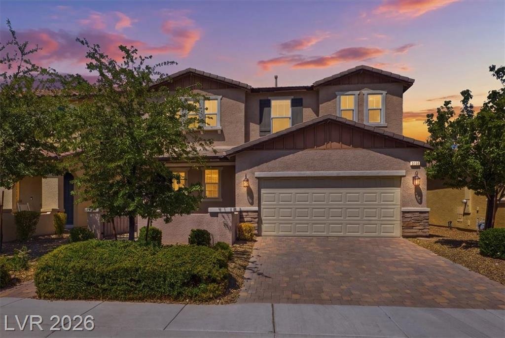 Front elevation at twilight with warm window light and a pink desert sunset at 3158 Biccari Avenue