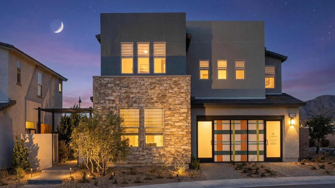 The Linea model home by Pardee Homes lit at twilight in Inspirada, Henderson NV, with stone accents and the Linea logo on the garage door