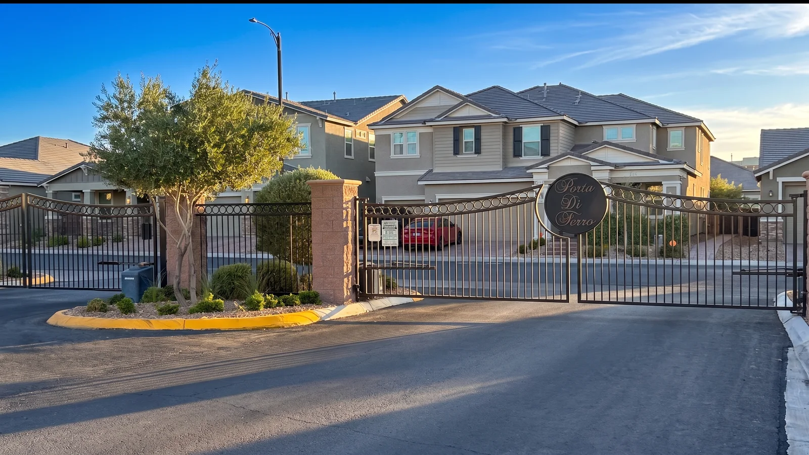 The Porta Di Ferro entrance gate in Inspirada, Henderson NV — bronze iron gate with the Porta Di Ferro medallion and two-story KB Home residences behind