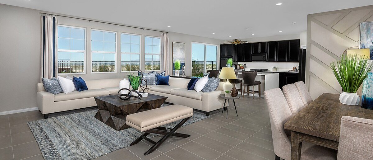 Open great room, dining area and kitchen inside a KB Home model at Reserves in Inspirada, Henderson NV, with tile floors and desert views through a wall of windows