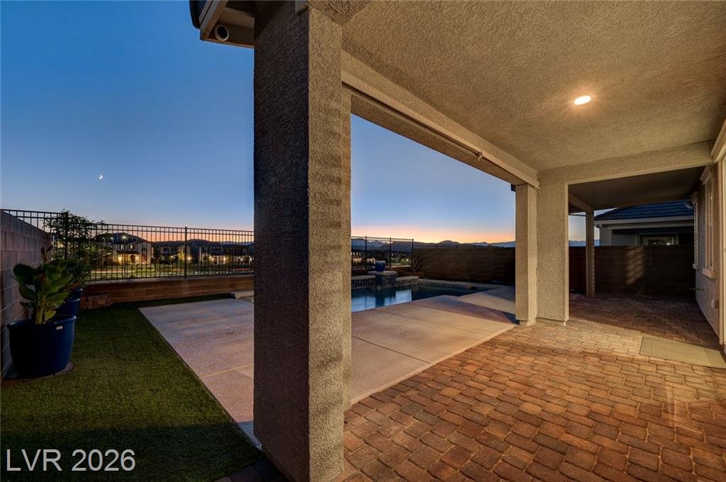Covered patio with paver flooring and recessed lighting beside the pool