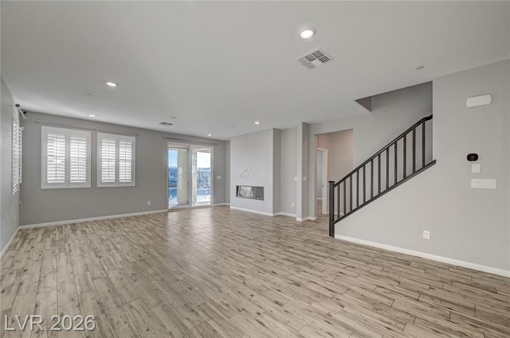 Living room at 2587 Tolmezzo Street with wood-look plank flooring and the staircase beyond