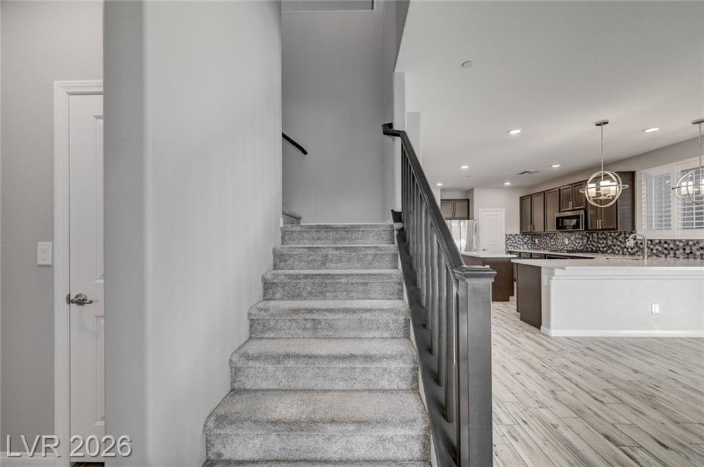 Carpeted staircase with iron balusters beside the kitchen