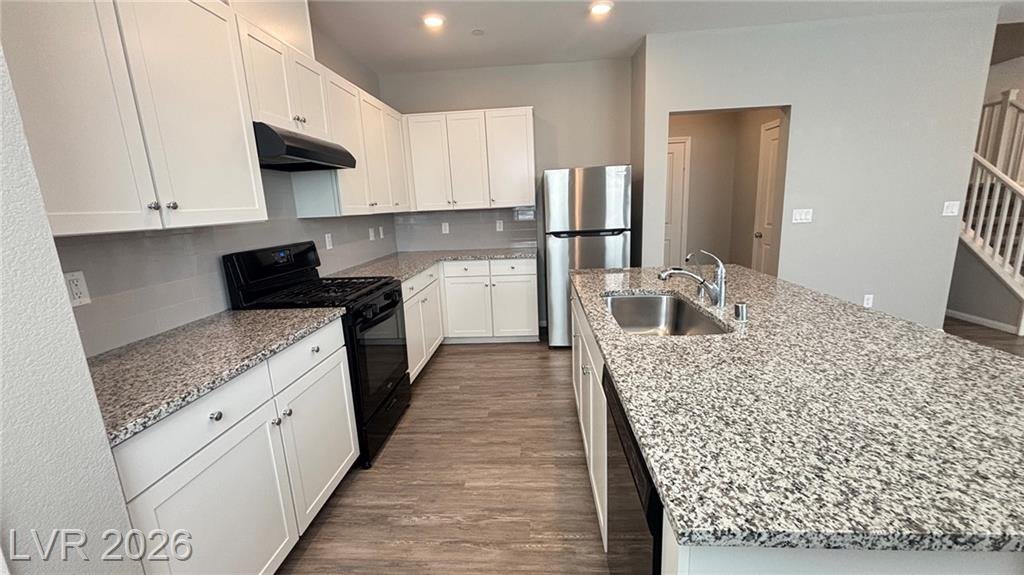 Stainless steel refrigerator, gas range and vent hood along the kitchen wall