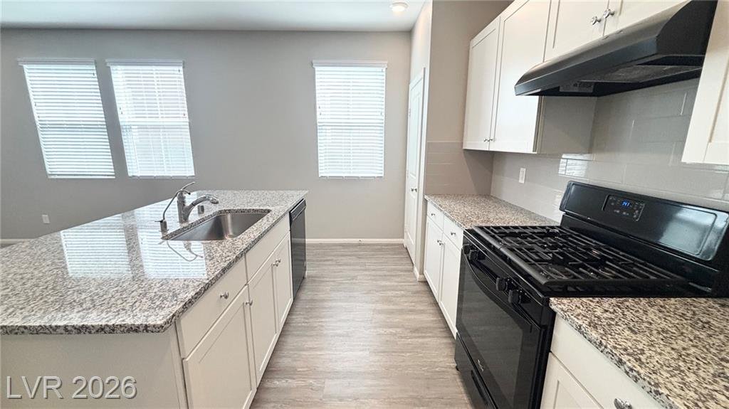 Kitchen sink under the window with granite counters and a gas stove