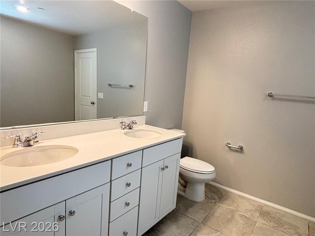 Primary bathroom double-sink vanity with tile flooring