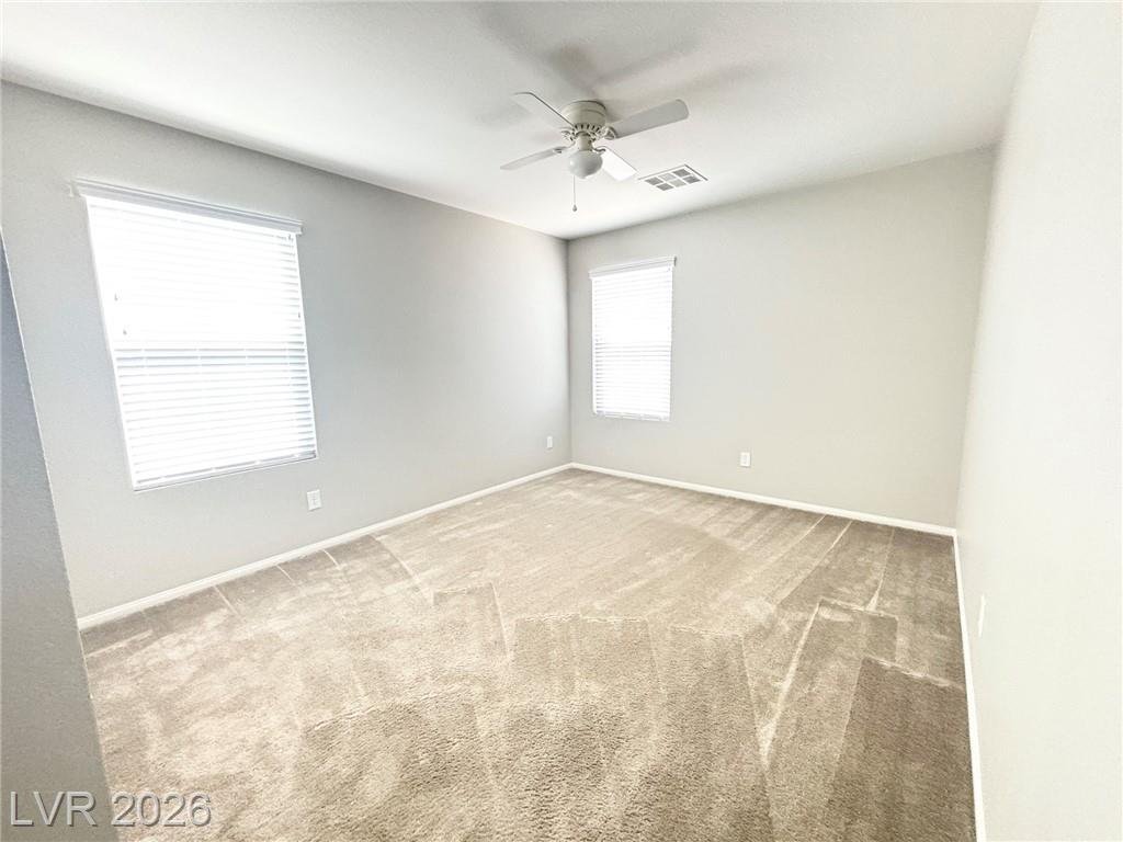 Second bedroom with a ceiling fan and dual windows
