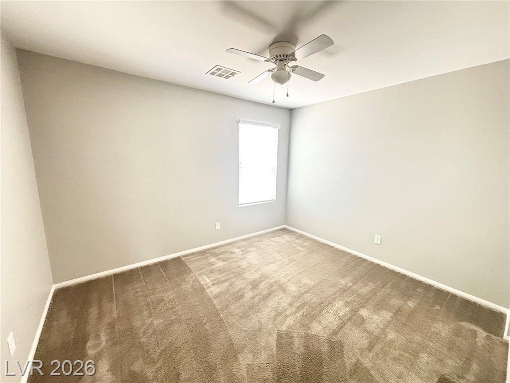 Third bedroom with a ceiling fan and carpet