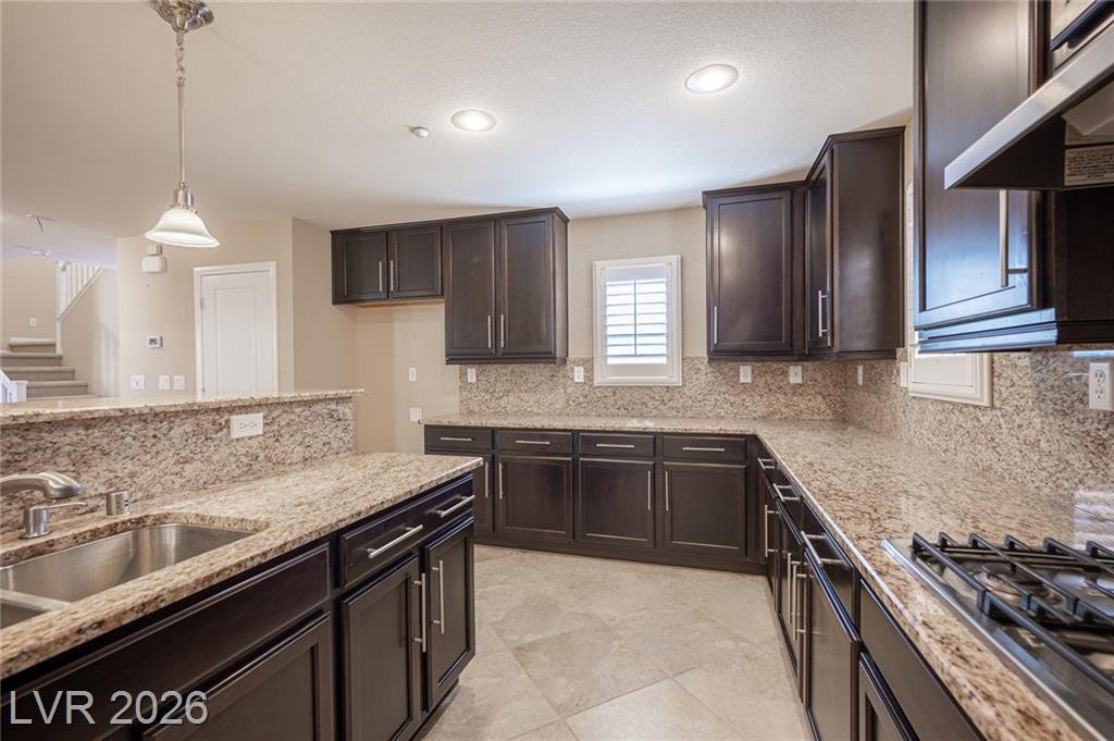 Granite counters and a gas cooktop along the kitchen wall