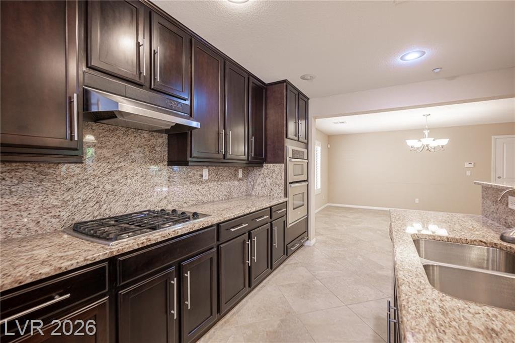 Gas cooktop, stainless hood and granite backsplash
