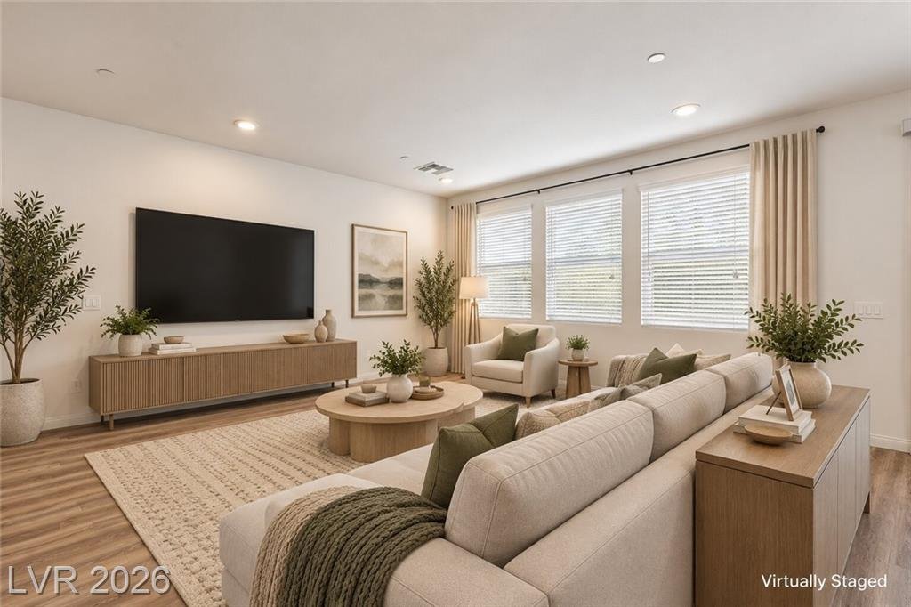 Great room with a wall of front windows, virtually staged