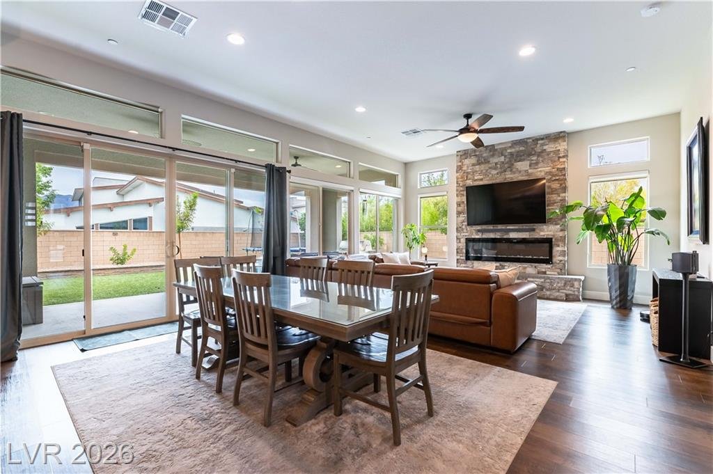 Great room with dining table, stone fireplace wall and sliding glass doors to the yard