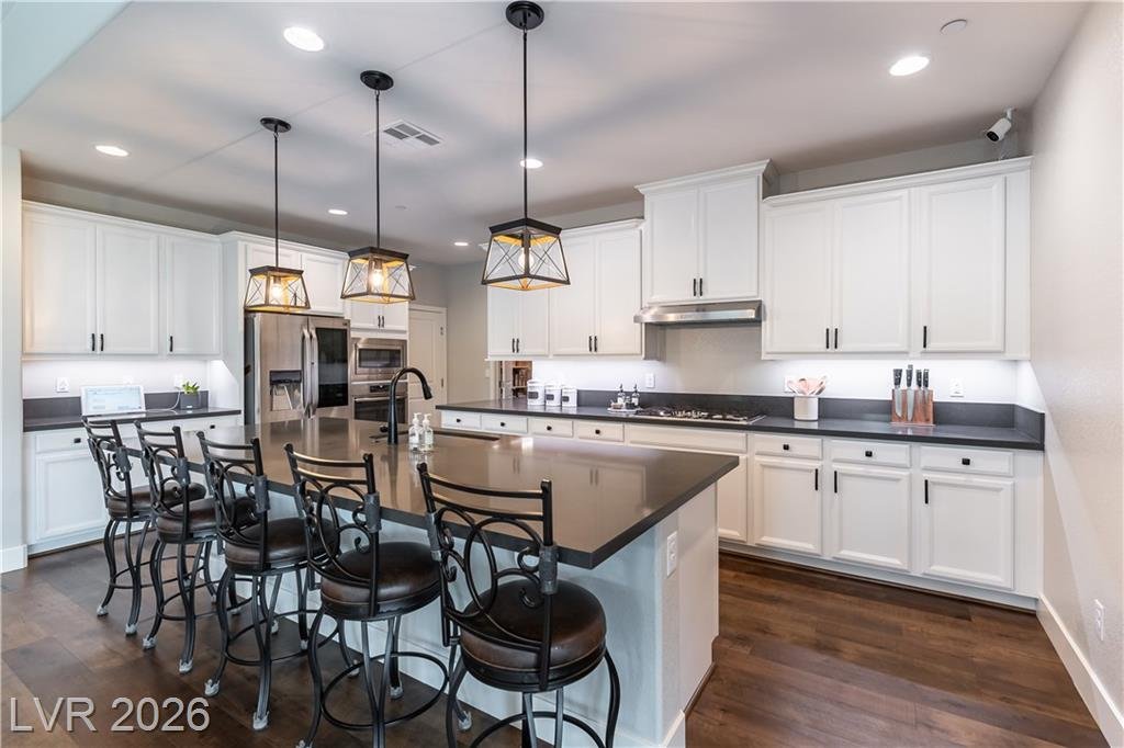 White shaker cabinets, stainless refrigerator and built-in oven along the kitchen wall