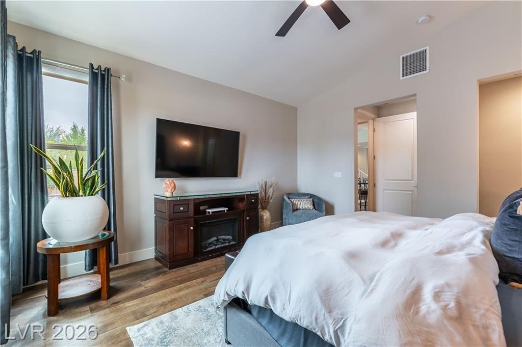 Primary bedroom sitting area with electric fireplace and wall-mounted TV