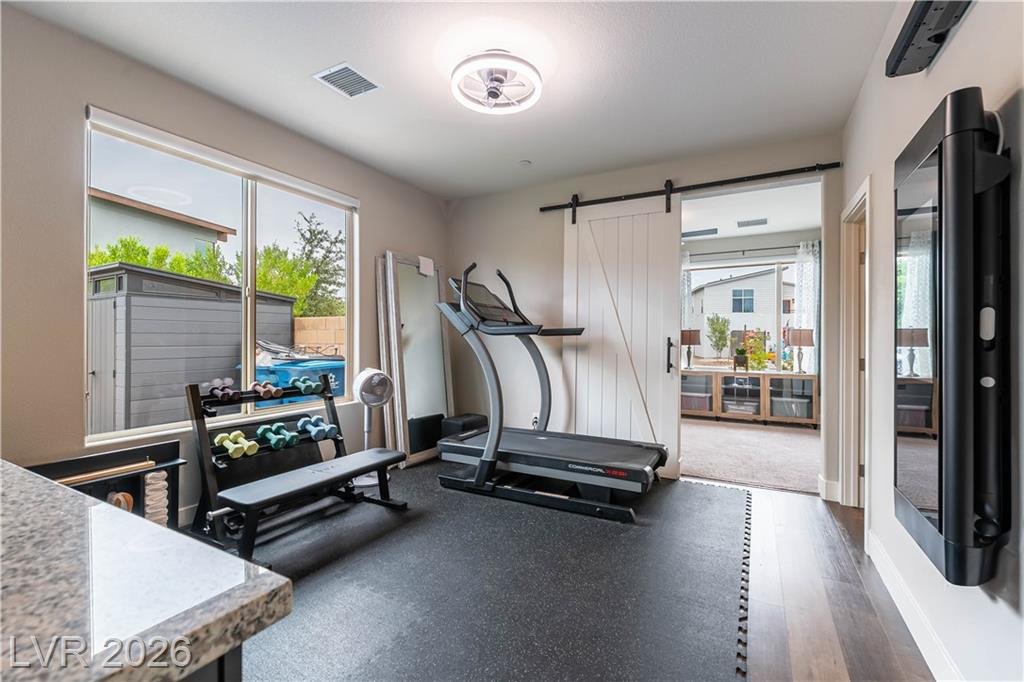 Home gym with rubber flooring, treadmill and barn door