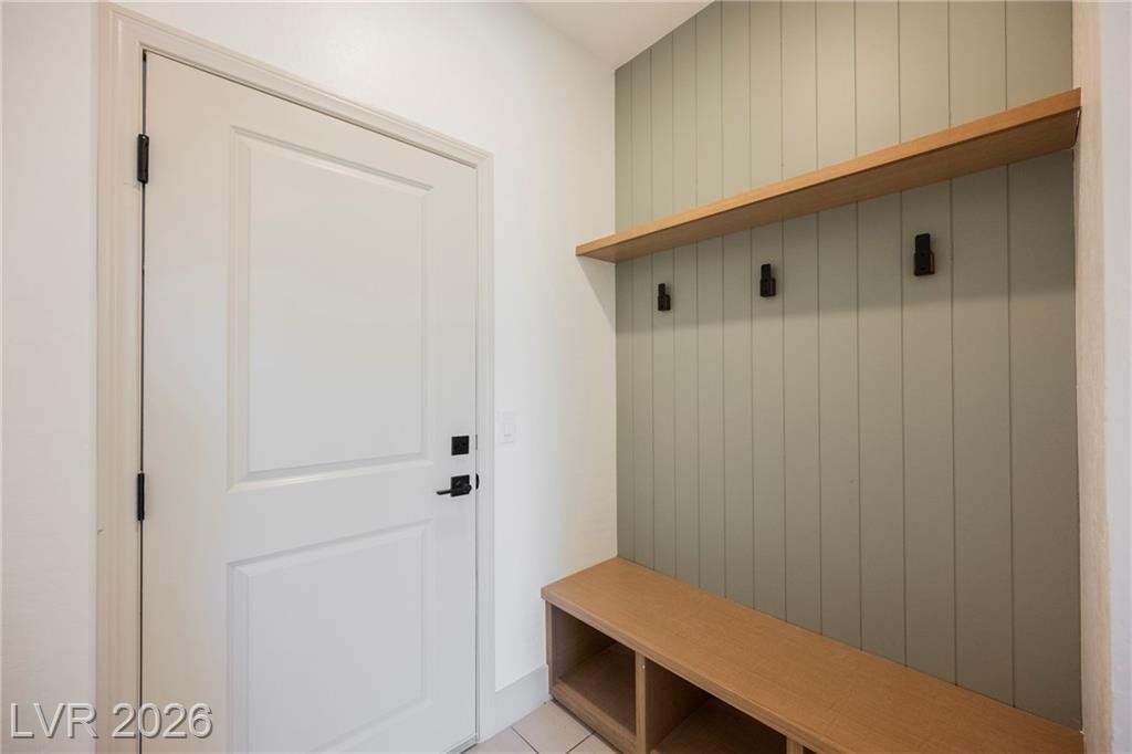 Drop zone bench with sage shiplap and wall hooks beside the garage entry door