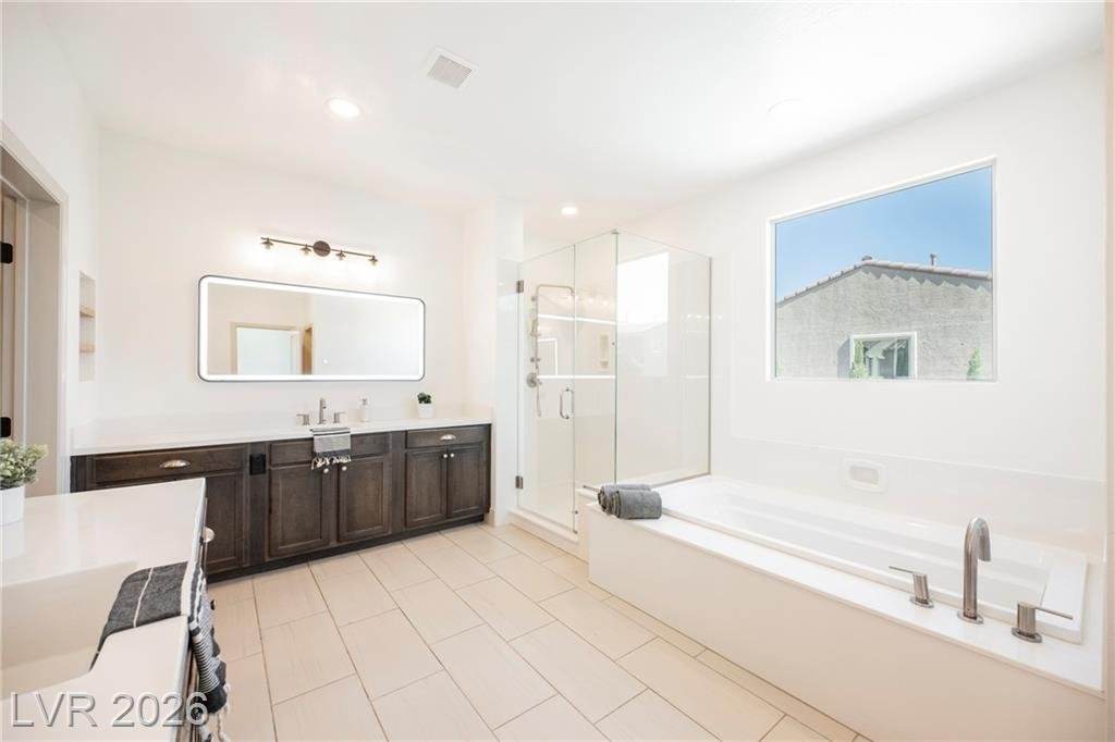 Primary bath with dark wood vanity, glass shower and soaking tub