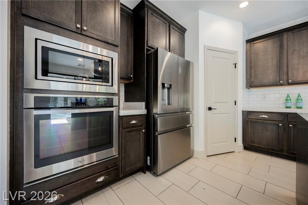 Built-in wall oven and microwave stack beside a stainless French-door refrigerator