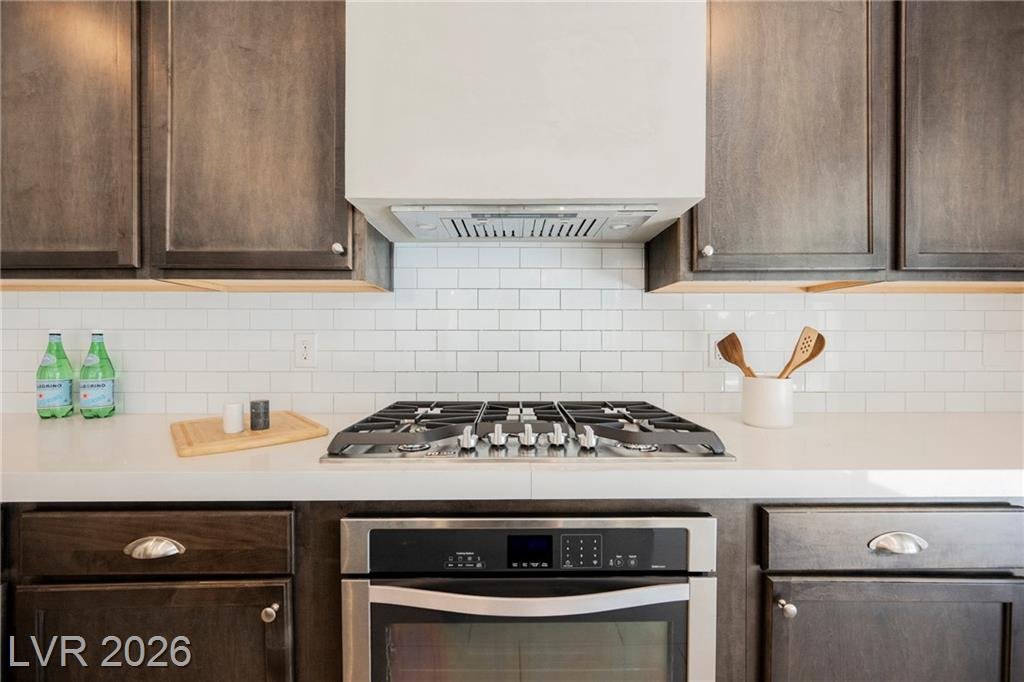 Gas cooktop under a plaster range hood with subway tile backsplash