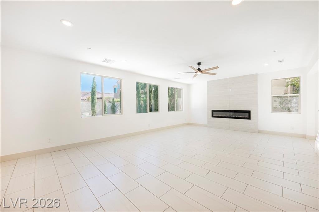 Great room with ceiling fan, tall windows and linear fireplace at 2430 Quiet Ode Street