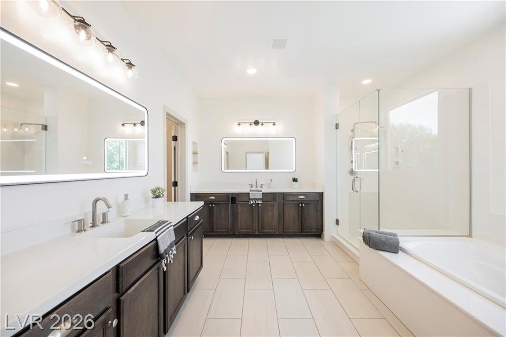 Primary bath with long double vanity, backlit mirrors and walk-in shower