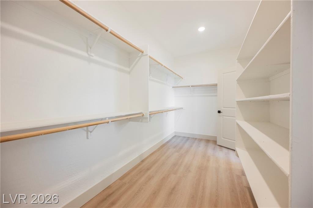 Primary walk-in closet with double hanging rods and built-in shelving