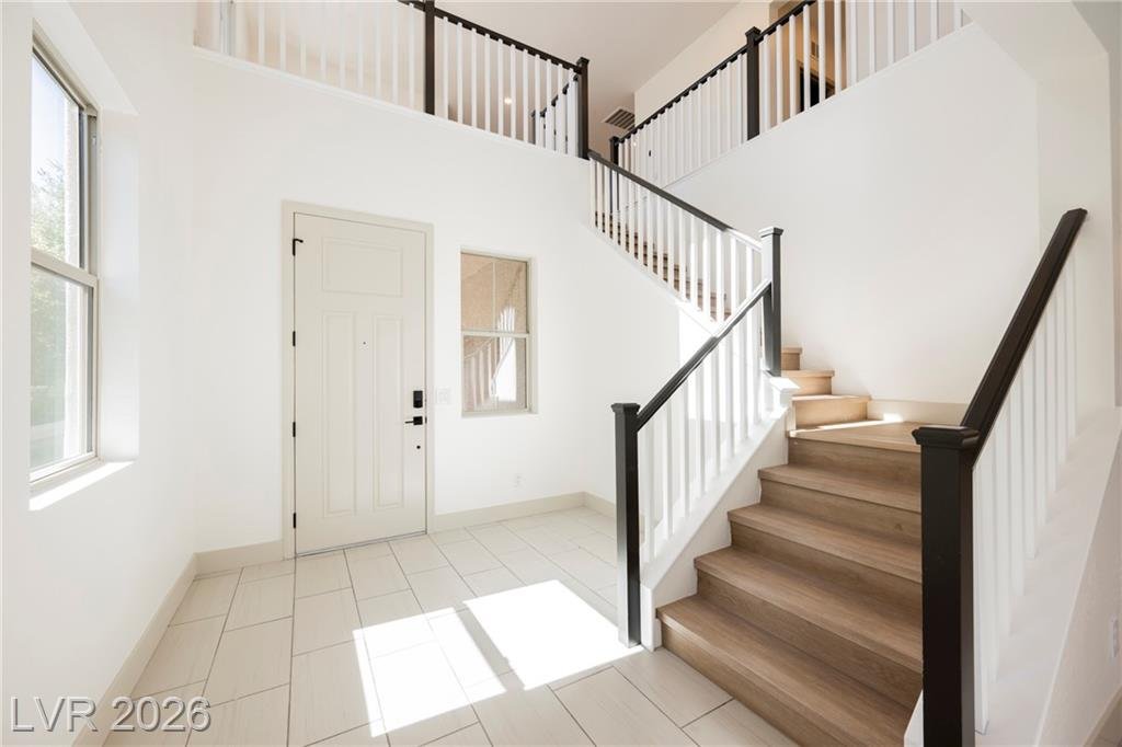 Two-story entry with wood staircase and black iron railing