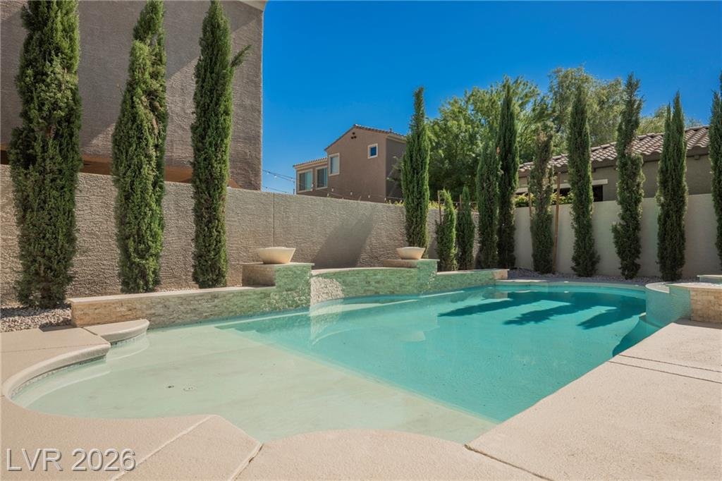 Pool with wet deck surrounded by tall cypress trees