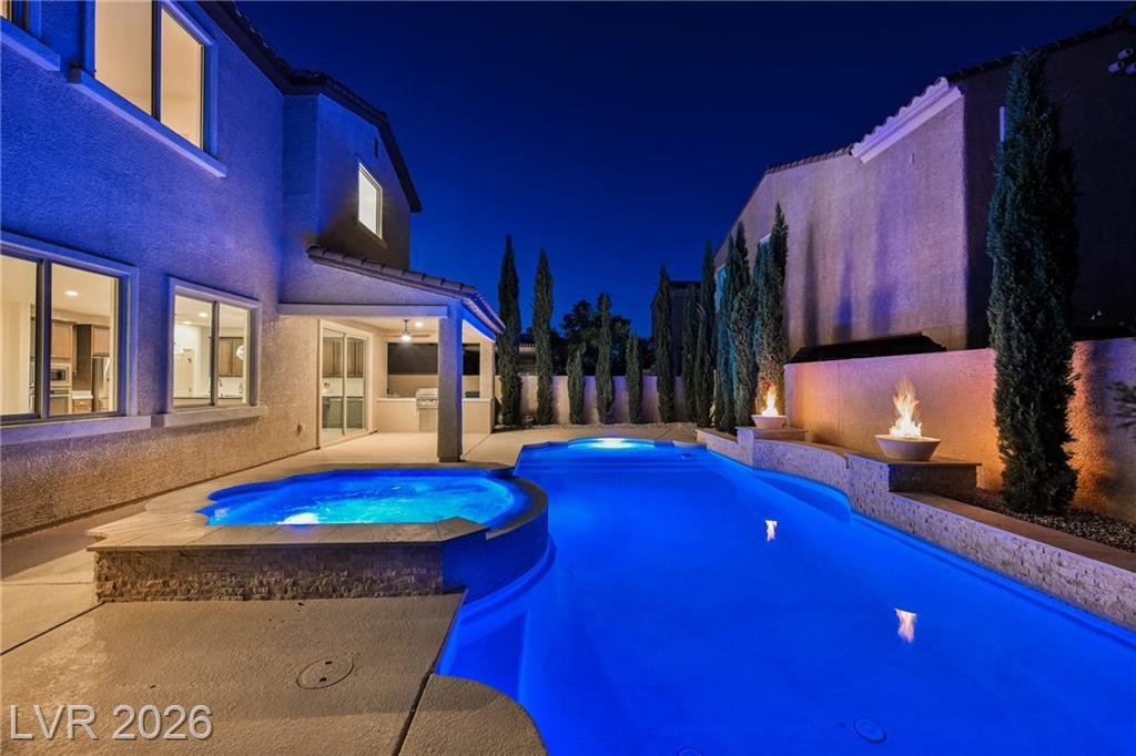 Pool, spillover spa and fire bowls glowing at night