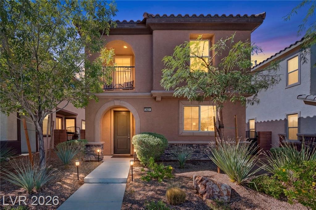 Two-story Spanish-style home at 2621 Marvel Astoria Street, Inspirada, lit at dusk with desert landscaping