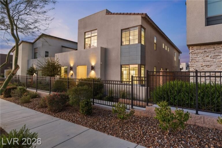 Front of 2702 Marchetti Place, a two-story Inspirada home with a wrought-iron fenced front yard at dusk