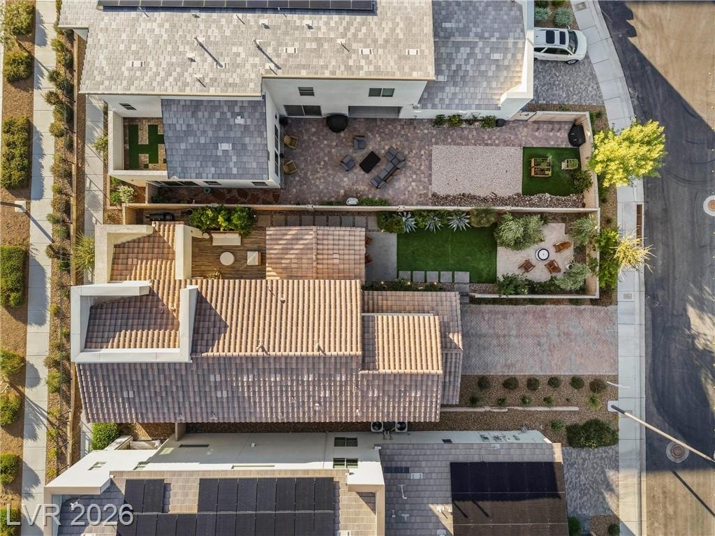 Overhead drone view of the tile roof, covered patio and landscaped backyard