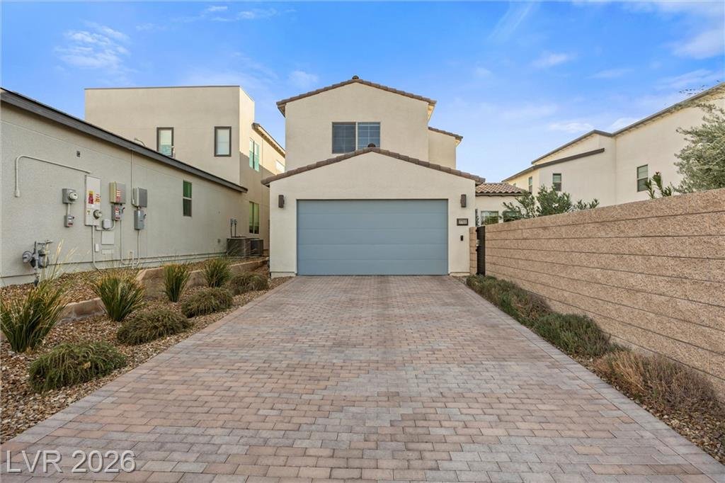 Paver driveway and blue garage door between block walls in daylight
