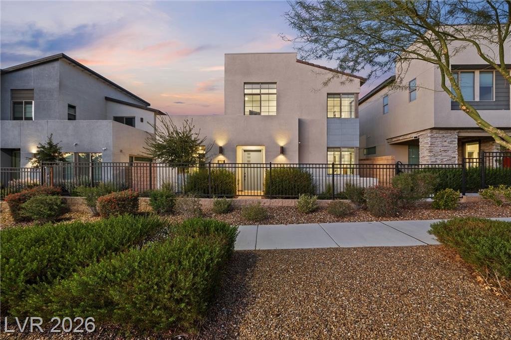 Front yard with iron fencing, wall sconces and drought-tolerant shrubs