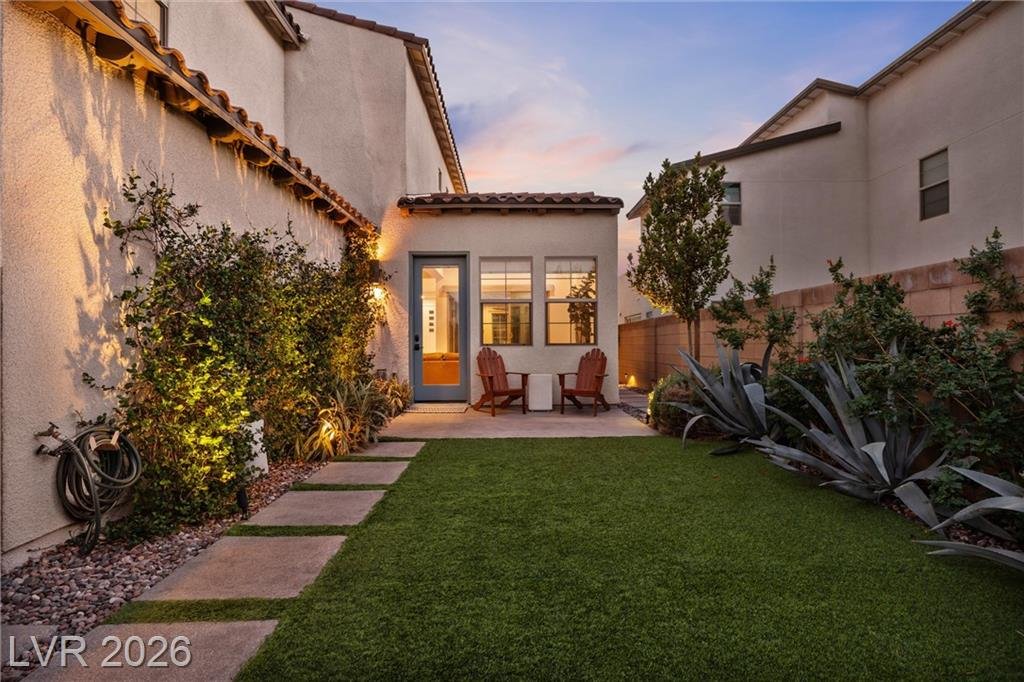 Stepping-stone path across the turf toward a lit glass patio door