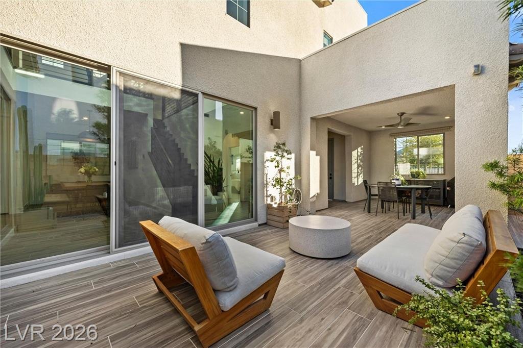 Tiled courtyard lounge with wood-frame chairs next to the sliding glass walls