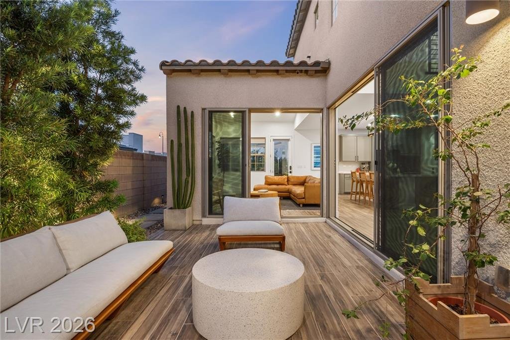 Courtyard sofa and round table at dusk with the great room lit beyond