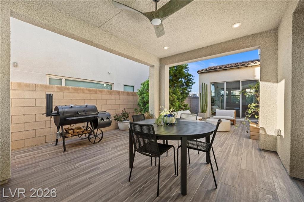 Covered patio dining table with a ceiling fan and a barbecue smoker