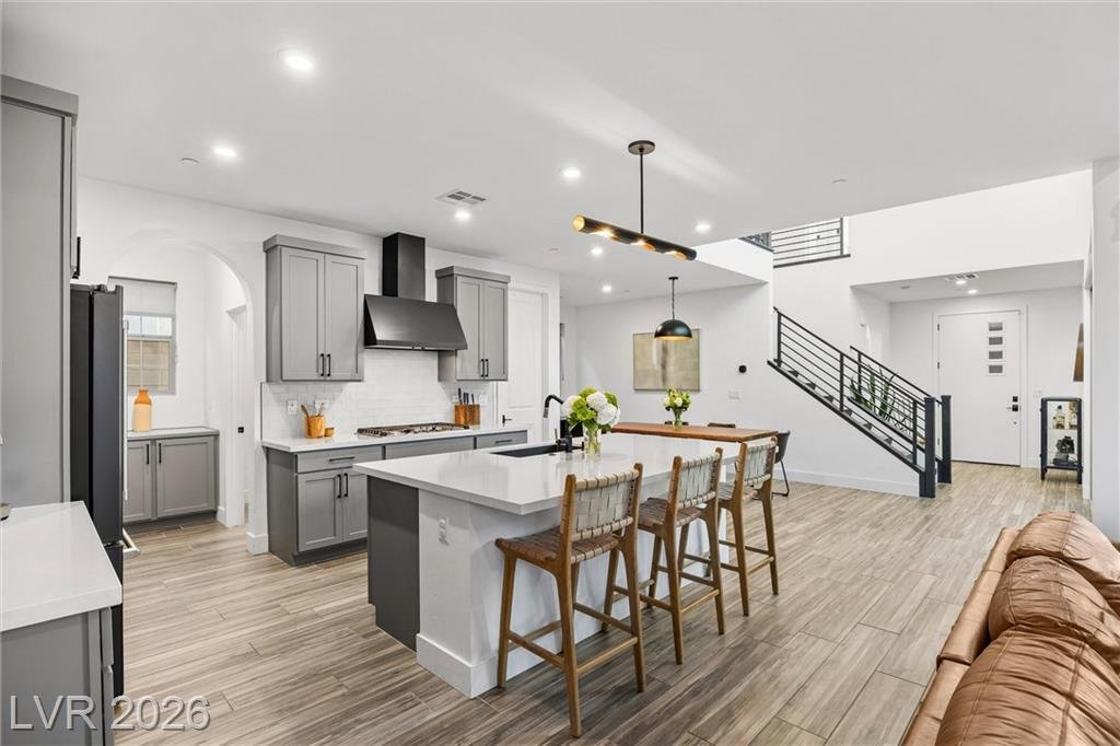 Kitchen with gray shaker cabinets, a quartz island and a chimney hood