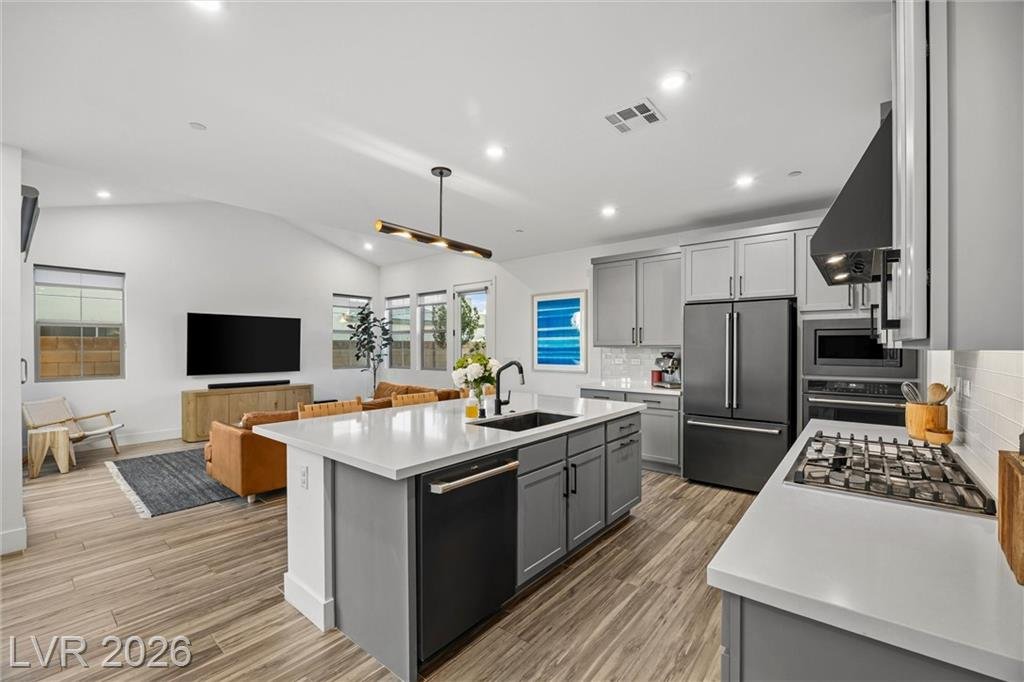 Kitchen island facing the built-in oven, microwave and refrigerator