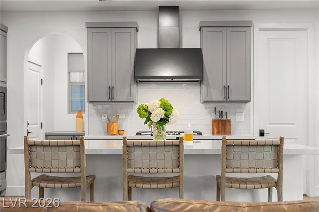Breakfast bar with woven stools beneath the vent hood and glass tile
