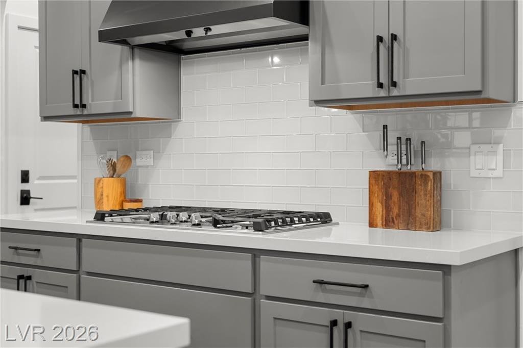 Five-burner gas cooktop with a white glass tile backsplash