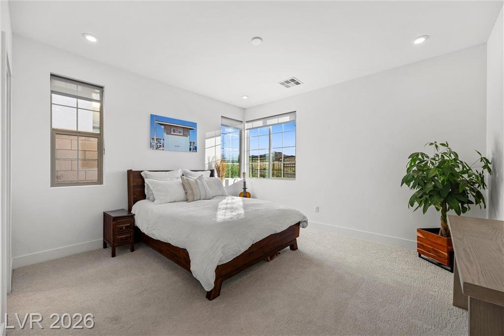 Downstairs guest bedroom with two windows and carpet