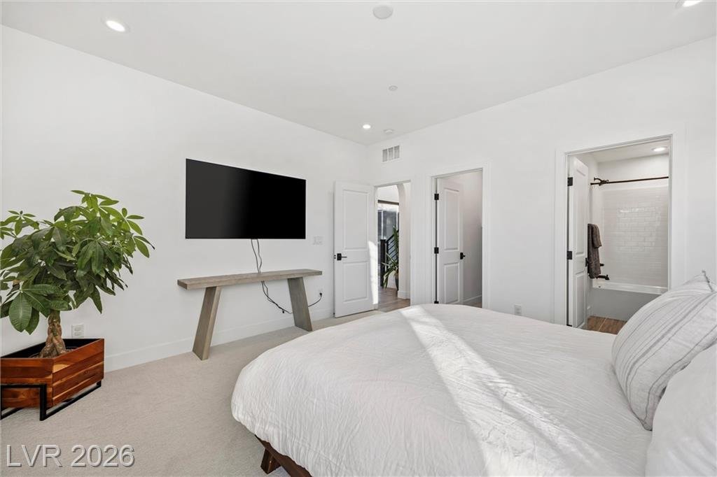 Downstairs bedroom with a TV and a doorway to its own bath