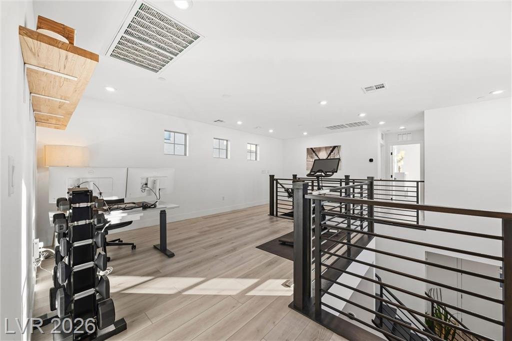 Loft with wood-look flooring and the black metal stair railing