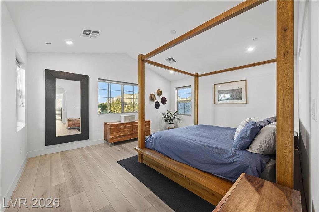 Primary bedroom with a canopy bed and wood-look flooring