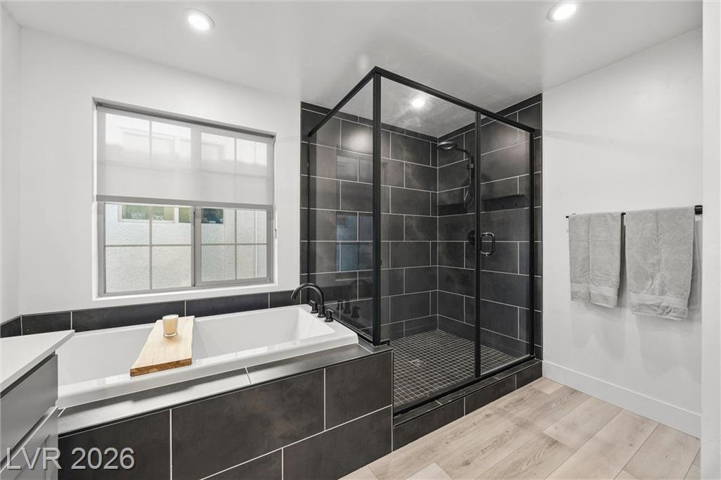 Garden tub beside a glass walk-in shower with dark tile