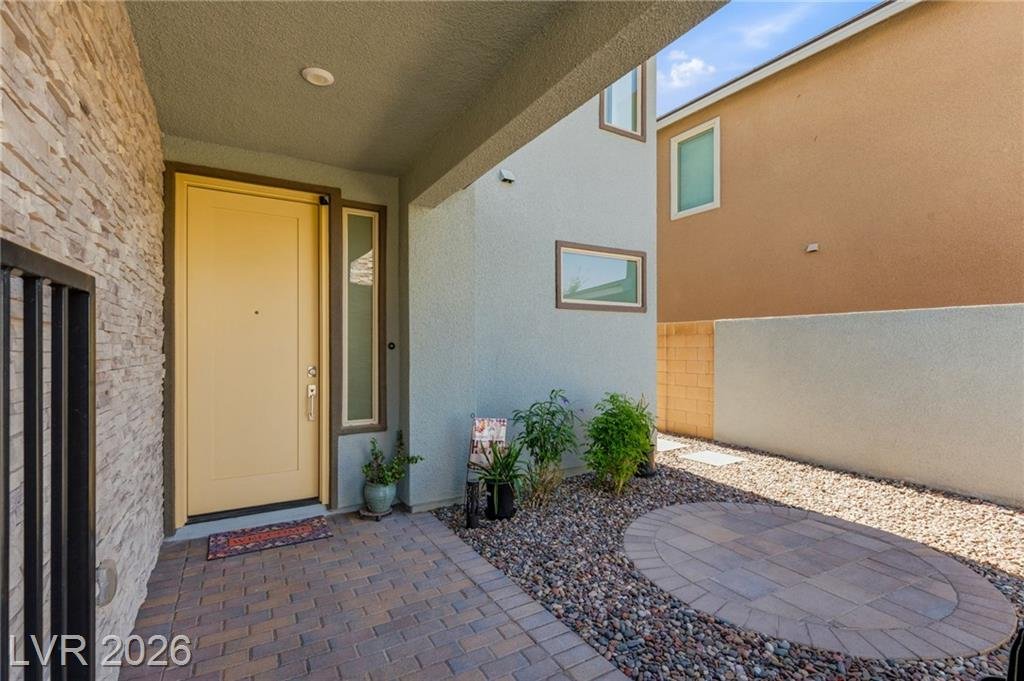 Yellow front door opening to a private courtyard with a round paver pad